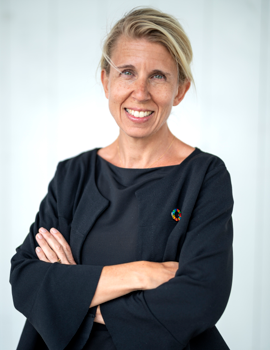 En kvinna med korslagda armar som ler.